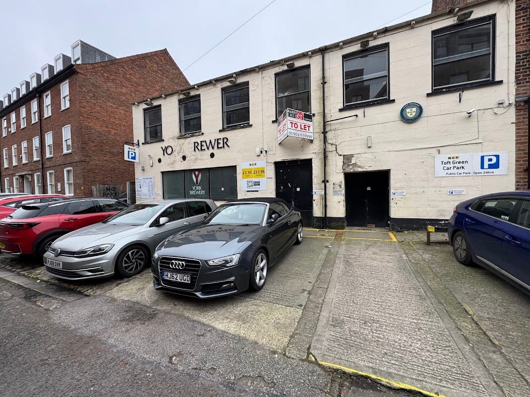 NCP Street Parking at Toft Green, featuring parked cars and a building with "TO LET" signage.